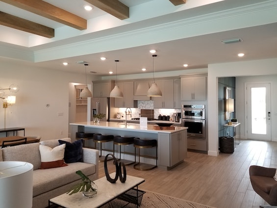 open concept living room and kitchen with wood flooring and neutral furniture